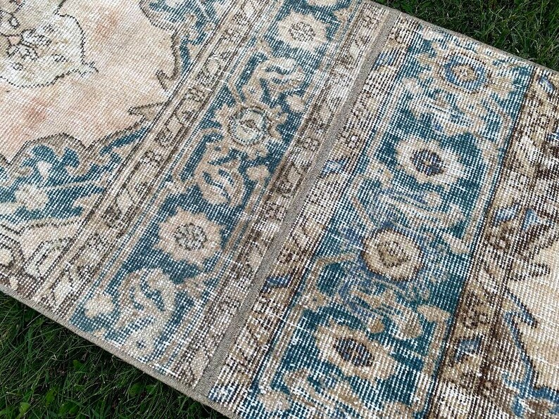 May include: A vintage rug with a blue and beige pattern. The rug has a faded look and is made of a soft, woven material.