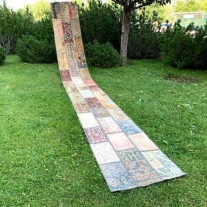 Könnte beinhalten: Ein langer, rechteckiger Patchwork-Teppich mit einer Vielzahl von Farben und Mustern. Der Teppich besteht aus kleineren Quadraten und Rechtecken aus verschiedenen Stoffen, die ein einzigartiges und vielseitiges Design schaffen.
