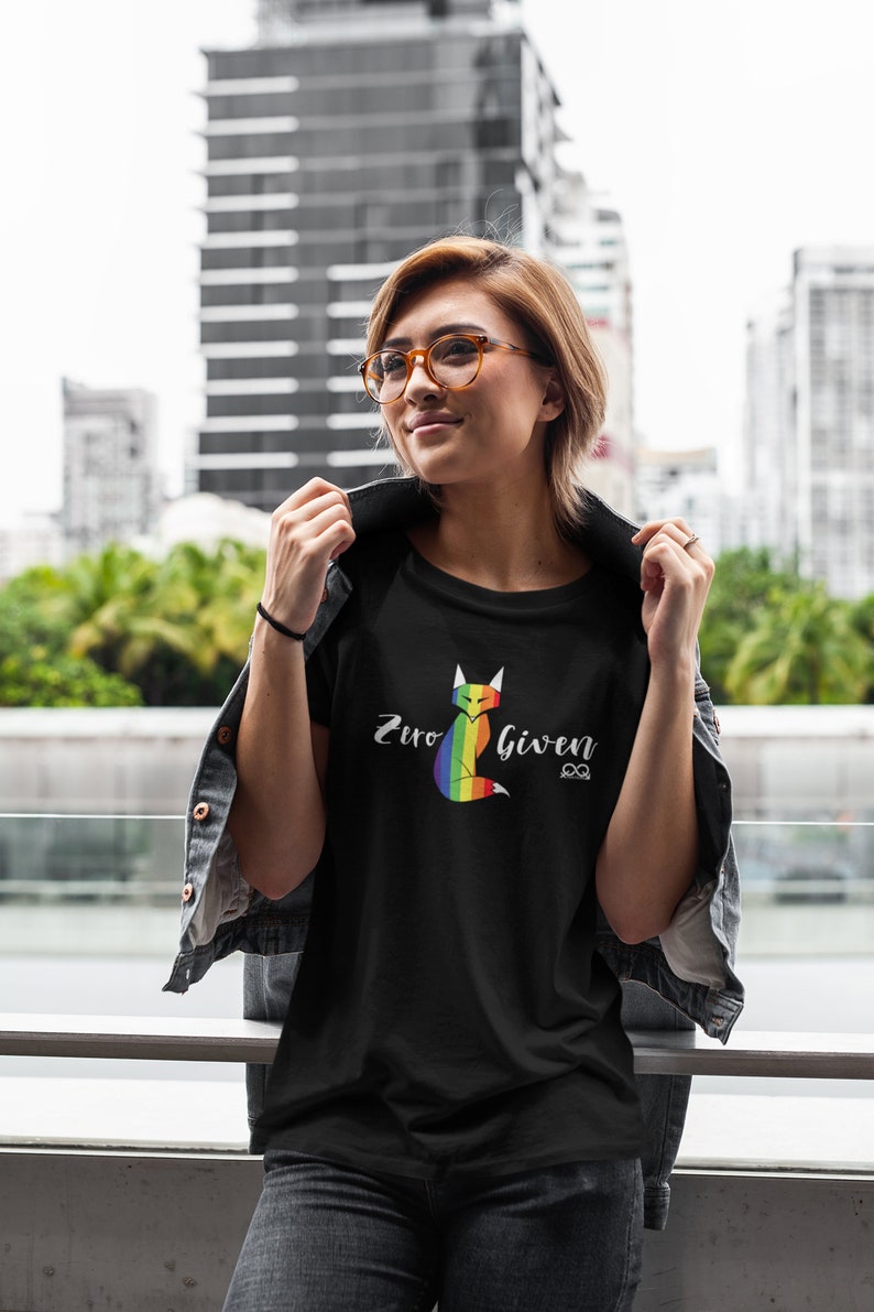 May include: A black t-shirt with a rainbow fox graphic and the text "Zero Given" in white lettering. The fox is sitting down with its tail curled around its body.