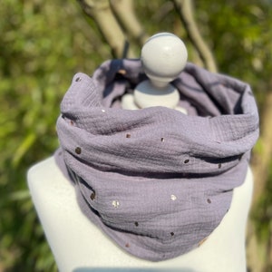 Könnte beinhalten: Ein weicher, grauer Schal aus Baumwolle mit einem dezenten Schimmer von goldenen Glitzerpunkten. Der Schal ist gefaltet und auf einer weißen Puppe ausgestellt.