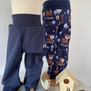 Könnte beinhalten: Zwei Paar blaue Leggings, eine mit einem Hirsch- und Waldmuster, auf Mannequins. Die Leggings werden auf einer weißen Oberfläche mit einer Vogelfigur und einem Vogelhaus präsentiert.