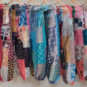 Può includere: Un gruppo di pantaloni patchwork colorati con una varietà di motivi floreali e geometrici. I pantaloni sono in cotone e hanno una cintura elastica.