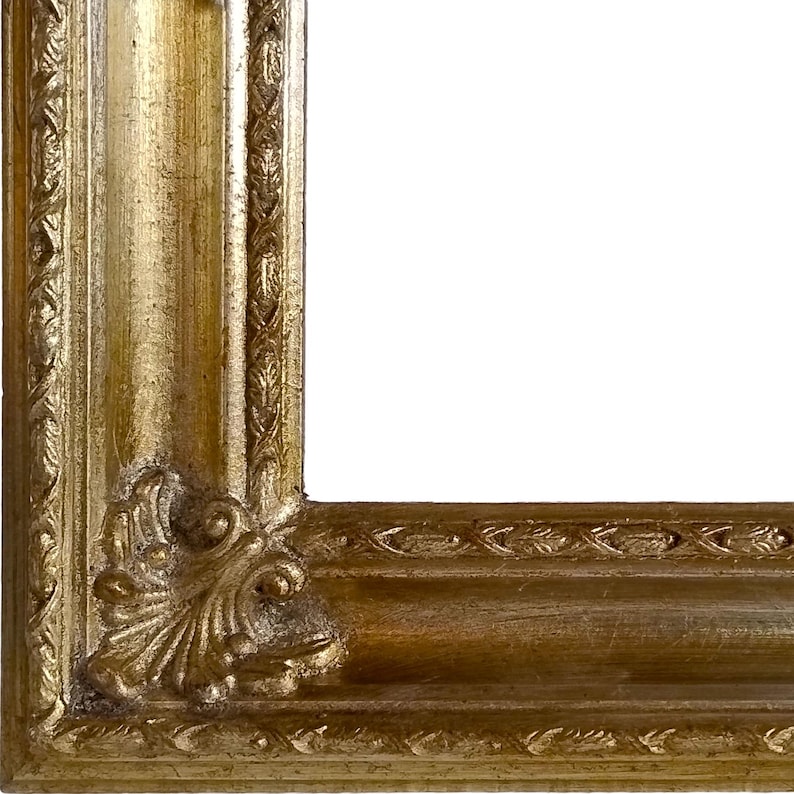 Op de afbeelding: Close-up van een gouden hoek van een fotolijst. Het frame heeft sierlijke details met een getextureerd oppervlak en een decoratief hoekontwerp. Het frame is leeg, met een witte achtergrond.