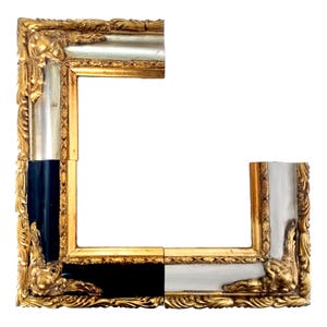 May include: Ornate picture frame with gold, silver, and black accents. The frame features detailed carvings and a rectangular shape, with a white background. The frame is partially assembled, showcasing its design and construction.