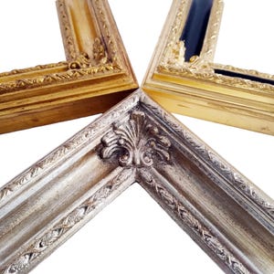 Op de afbeelding: Close-up van vier hoeken van sierlijke fotolijsten. De lijsten zijn goud, zilver en zwart, met gedetailleerde gravures en decoratieve randen. De hoeken zijn in een stervorm gerangschikt tegen een witte achtergrond.