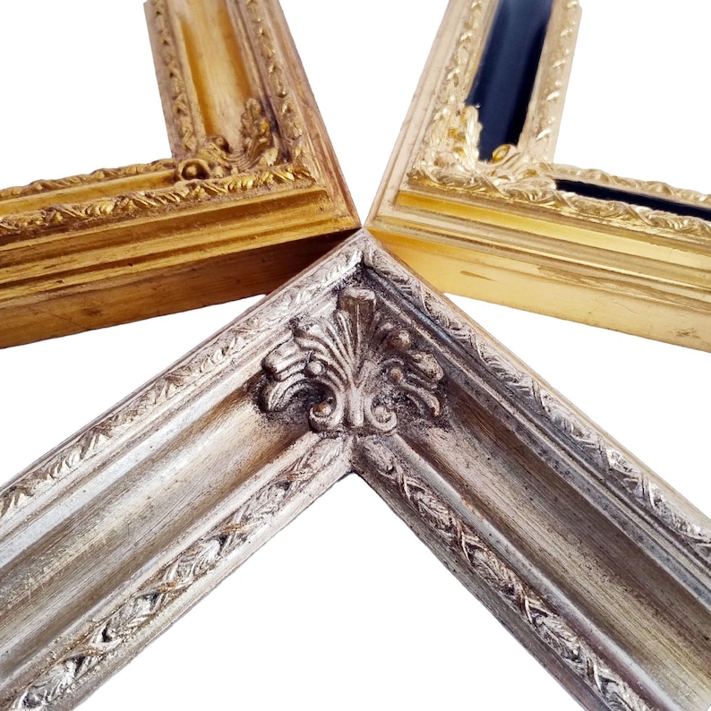 Op de afbeelding: Close-up van vier hoeken van sierlijke fotolijsten. De lijsten zijn goud, zilver en zwart, met gedetailleerde gravures en decoratieve randen. De hoeken zijn in een stervorm gerangschikt tegen een witte achtergrond.