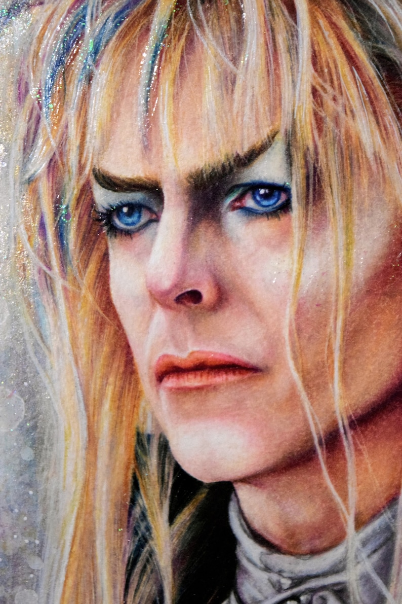 May include: A close-up portrait of a person with long, blonde hair. The person has blue eyes and is wearing makeup. The person has a serious expression on their face.
