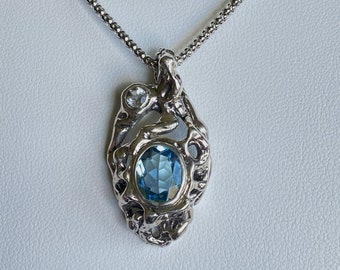 Gnarled Cast Setting Surrounds Large Faceted Blue Topaz Accented by Petite Faceted Aquamarine Gemstone.