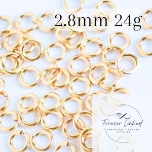 May include: A close-up of a pile of 24 gauge, 2.8 mm gold jump rings. The jump rings are small and round, and they are perfect for jewelry making.