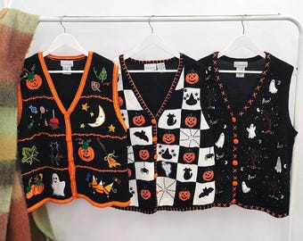May include: Three black and white knit sweater vests featuring Halloween motifs. The left vest has orange trim and pumpkin, ghost, and candy designs. The center vest has a black and white checkerboard pattern with pumpkins and cats. The right vest has ghost and tree patterns.