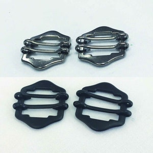May include: Two sets of metal and plastic slider buckles. The metal buckles are silver and the plastic buckles are black.