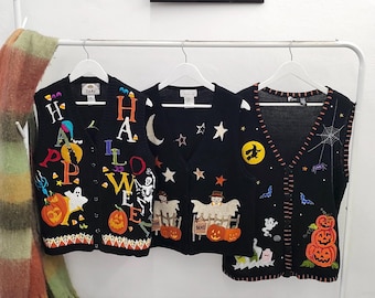 Puede incluir: Tres chalecos de punto negro con bordados temáticos de Halloween. El chaleco izquierdo muestra la palabra HALLOWEEN con calabazas, un fantasma y un esqueleto. El chaleco central presenta estrellas, lunas y espantapájaros. El derecho muestra calabazas, una telaraña y una bruja.