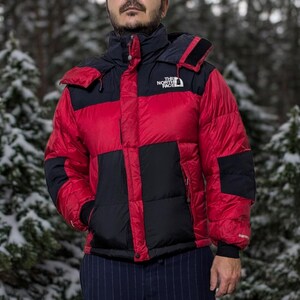 May include: A red and black puffer jacket with a black hood and the text "THE NORTH FACE" on the front.