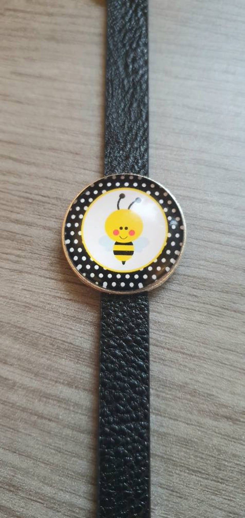 Black strap bracelet with a 25mm cute bee cabachon bezel.