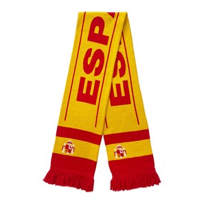 May include: A yellow and red scarf with the word "ESPAÑA" written in red letters. The scarf has a fringe on the bottom and features the Spanish coat of arms.