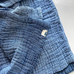 May include: A blue cotton waffle weave throw blanket with a small white tag that says "Made in Japan".