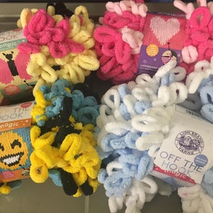 May include: Four skeins of Lion Brand Off The Hook Magic yarn in various colors, including pink, yellow, blue, and white. Each skein has a label with the brand name and the words "Off The Hook Magic".