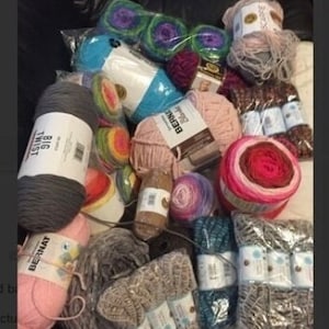 May include: A collection of yarn in various colors and textures, including gray, pink, blue, and brown. Some of the yarn is in skeins, while others are in balls. There are also some knitted items in the image, such as a gray scarf and a pink hat.