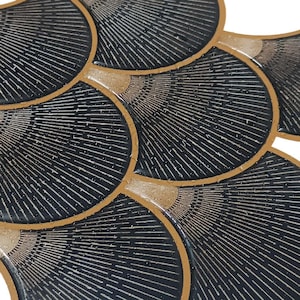 Black Egyptian peel-and-stick tile set in overlapping scallop shapes with tan borders for a 3D vinyl backsplash.