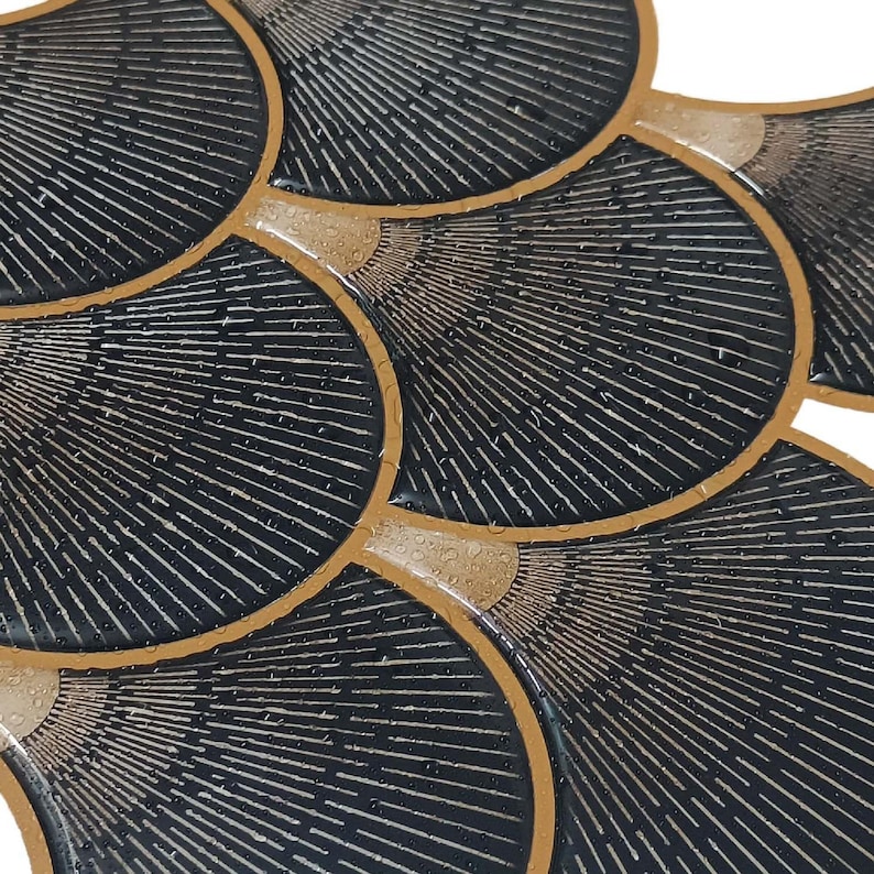 Black Egyptian peel-and-stick tile set in overlapping scallop shapes with tan borders for a 3D vinyl backsplash.