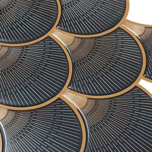 Black Egyptian peel-and-stick tile set in overlapping scallop shapes with tan borders for a 3D vinyl backsplash.