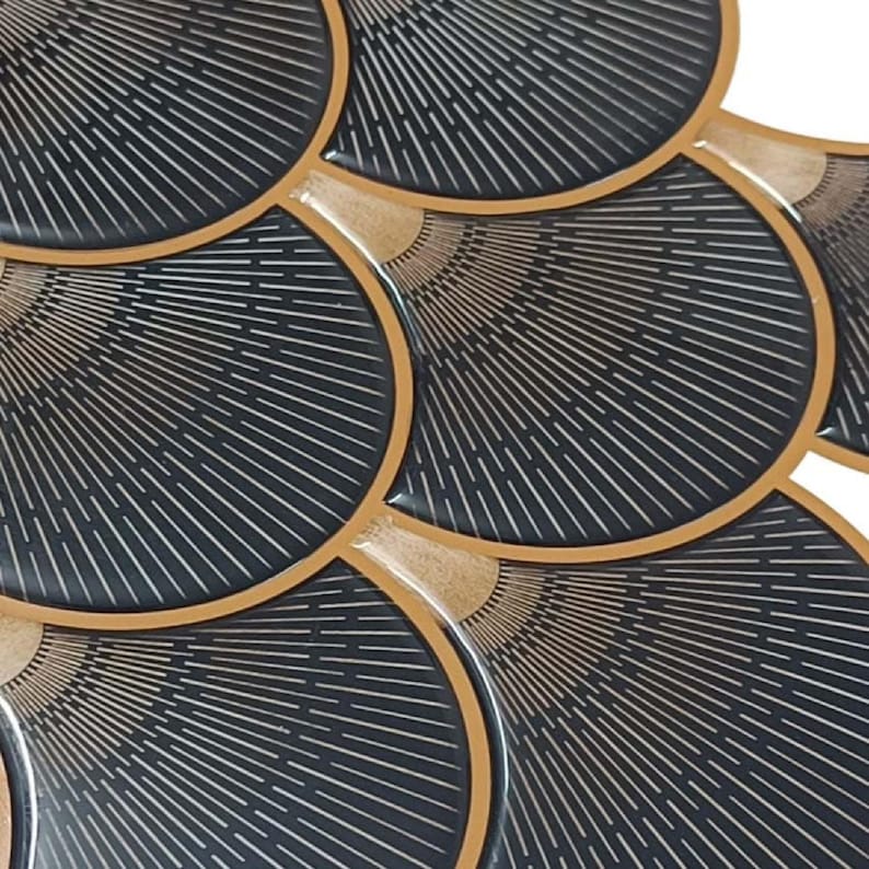 Black Egyptian peel-and-stick tile set in overlapping scallop shapes with tan borders for a 3D vinyl backsplash.