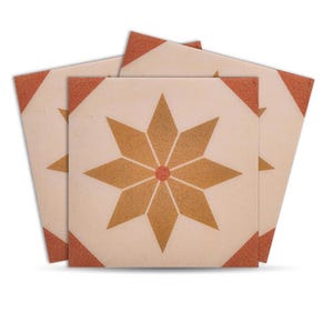 Op de afbeelding: Een stapel vierkante tegels met een sterrenpatroon. De tegels hebben een beige achtergrond met een grote, achtpuntige ster in bruintinten en een rood centrum. Elke tegel heeft een rode driehoek in elke hoek.