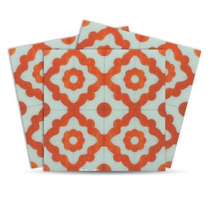 Op de afbeelding: Vierkante decoratieve tegels met een herhalend oranje bloemenpatroon op een lichtblauwe achtergrond. Het ontwerp heeft een centrale bloemvorm omringd door vier symmetrische bloemmotieven, wat een geometrische en artistieke uitstraling creëert. De tegels zijn in een waaier opgesteld.