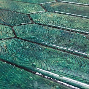 Angled close shot showing printed darker grout lines and glossy 3D picket texture on green peel and stick wall tiles