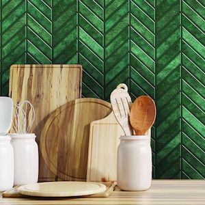 Puede incluir: Una colección de tablas de cortar de madera y utensilios de cocina, que incluyen una tabla redonda, una tabla rectangular, una cuchara y una espátula. Los artículos están dispuestos sobre una encimera de madera frente a una pared con patrón de chevron verde.