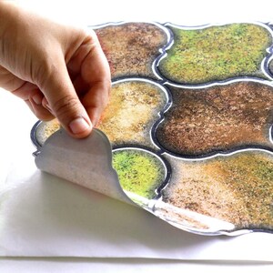 3D peel-and-stick wall tile grid with scalloped square tiles in moss green, brown, and tan for an earthy kitchen backsplash.