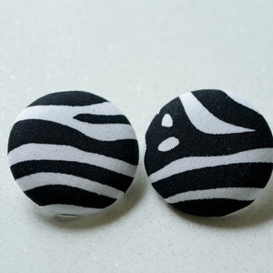 May include: A pair of black and white zebra print fabric button earrings.