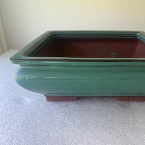 May include: A set of three ceramic nesting bowls in shades of blue, green, and white. The bowls feature a speckled glaze and a simple, modern design. The largest bowl is approximately 6 inches in diameter.