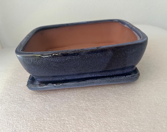 May include: A rectangular ceramic bonsai pot with a deep blue glazed exterior and a natural terracotta interior. The pot features rounded corners and sits on a matching rectangular blue glazed drip tray, creating a cohesive set for planting.