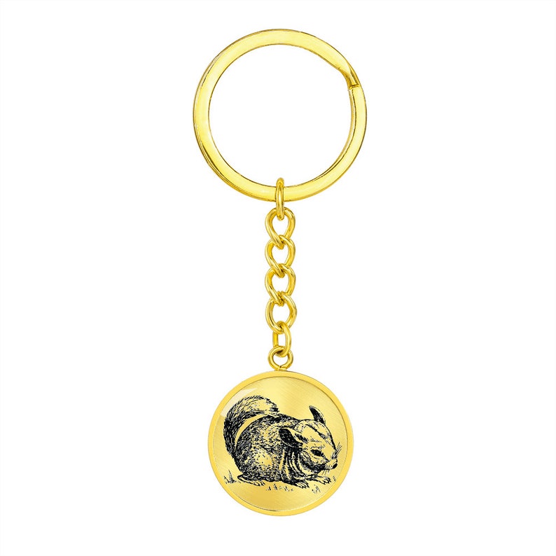 May include: Gold-colored keychain with a round metal charm featuring a black and white illustration of a chinchilla.