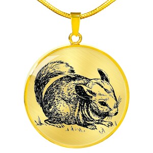May include: A gold necklace with a round pendant featuring a black and white line drawing of a chinchilla. The chinchilla is sitting on a gold background.