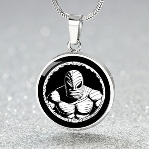 May include: A silver necklace with a round pendant featuring a black and white illustration of a masked figure with a muscular physique.