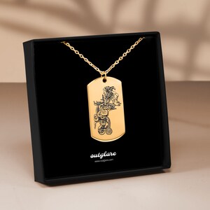 May include: Gold-colored dog tag pendant with a detailed black engraved design of a figure. The pendant hangs from a delicate gold chain and is presented in a black box. The brand name "outglare" is printed at the bottom.