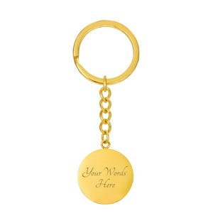May include: A gold-coloured keyring with a round pendant. The pendant has the text "Your Words Here" engraved on it. The keyring includes a ring and a chain of small links.