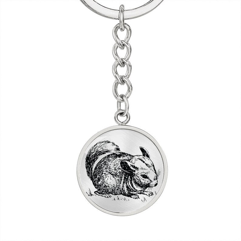 May include: A silver keychain with a round charm featuring a black and white line drawing of a chinchilla.