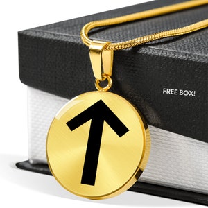 May include: A gold-colored pendant necklace with a black arrow symbol on a round, brushed metal pendant. The necklace is displayed on a black box with the words "FREE BOX!" printed on the side.