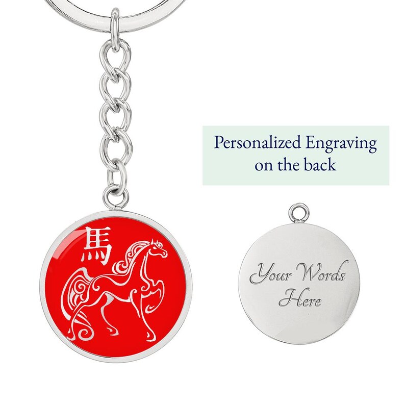 May include: A silver keyring with a red pendant featuring a white horse design and Chinese characters. The keyring includes a separate blank pendant with the text "Your Words Here" and the words "Personalized Engraving on the back".