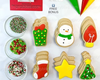 May include: A set of Christmas cookie decorating supplies with six different cookie shapes: a gift box, snowman, light bulb, stocking, star, and Christmas tree. The set includes three bowls of sprinkles, four piping bags, two wooden decorating tools, and a small bag of black and white sprinkles. The text "FREE BONUS" is printed on a white background.