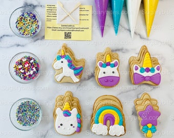 Op de afbeelding: Een set unicorn en regenboog-thema suikerkoekjes met sprinkles en glazuurzakjes. De koekjes zijn versierd met paars, blauw, geel en wit glazuur. De sprinkles zijn veelkleurig.