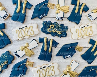 Peut inclure: Assortiment de biscuits en sucre sur le thème de la remise de diplômes, décorés de glaçage bleu, blanc et or. Les biscuits représentent un bonnet de graduation, un diplôme, une robe et l'année 2023. Un biscuit est personnalisé avec le nom "Eva".