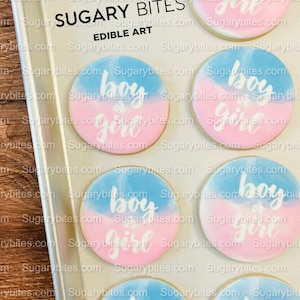 May include: Six round sugar cookies decorated with a blue and pink watercolour design. The cookies are decorated with white icing and the words "boy or girl" on each cookie.