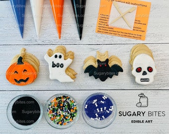 May include: A Halloween cookie decorating kit with four pre-iced cookies, four icing bags, three bowls of sprinkles, and a wooden tool for decorating. The cookies are shaped like a pumpkin, ghost, bat, and skull. The icing bags are blue, white, orange, and black. The sprinkles are black, multi-colored, and purple. The kit includes instructions for decorating the cookies. The kit is labeled "Sugary Bites Edible Art".