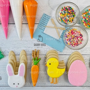 May include: A set of Easter cookie decorating supplies including four icing bags, four cookie cutters, two bags of sprinkles, one bag of sanding sugar, and four pre-iced cookies. The cookies are shaped like a bunny, a carrot, a chick, and an egg. The icing bags are yellow, pink, white, and orange. The sprinkles are multi-colored and the sanding sugar is green. The text on the blue card reads "Thank you and enjoy!" and "Sugary Bites Cookie Art".