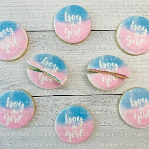 May include: Nine round sugar cookies decorated with blue and pink icing. The cookies are decorated with the words "boy or girl" in white icing.