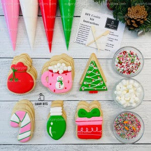 May include: A Christmas cookie decorating kit with six pre-baked cookies, four decorating bags, sprinkles, mini marshmallows, and two wooden sticks. The cookies are decorated with Christmas themes, including a snowman, a Christmas tree, a gift, a candy cane, a light bulb, and a Santa sack. The kit includes instructions for decorating the cookies.
